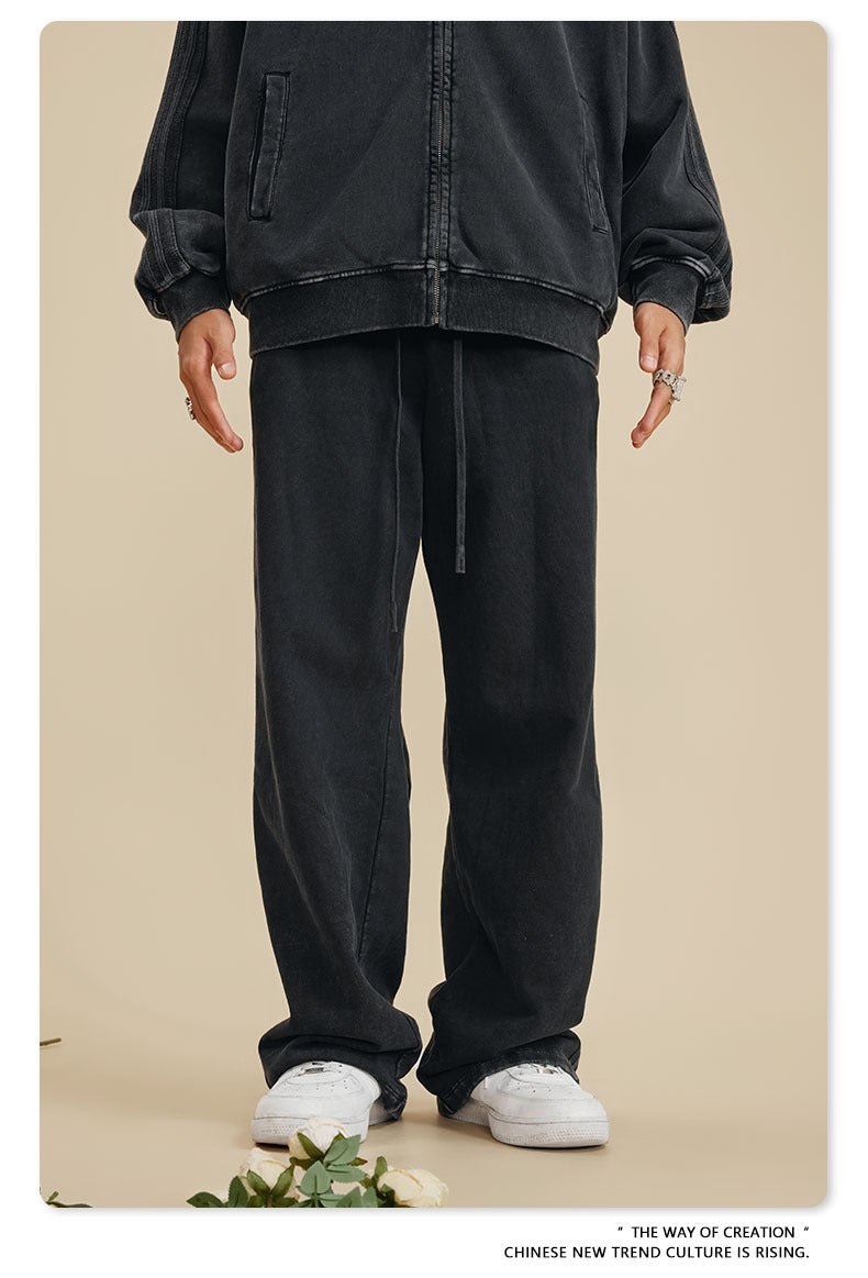 Front view of person in black zip-up hoodie and matching sweatpants on beige background with flower accents