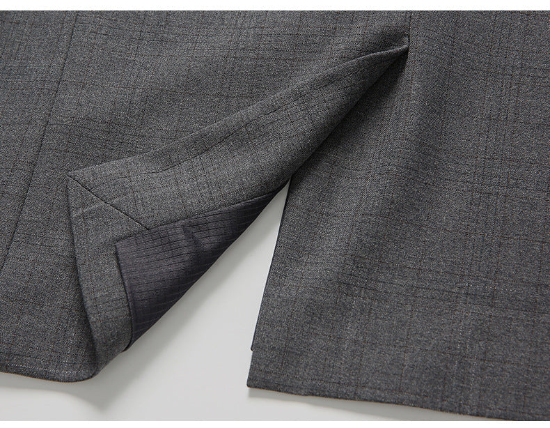 Detail of gray suit jacket vent showing craftsmanship of tailored seam and center split on textured wool fabric
