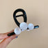 A black resin hair claw with glossy white beads, held between fingers with glossy nail art.
