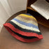 A colorful crochet bucket hat featuring deep rainbow stripes and a bold red-trimmed brim, offering a lively statement look.