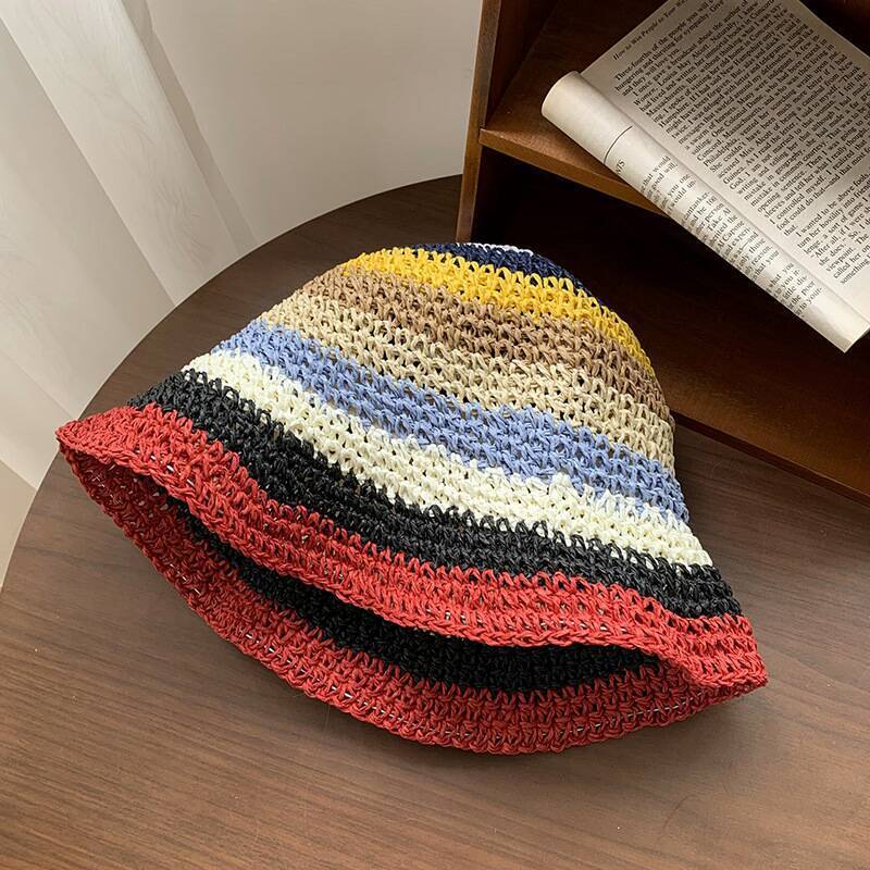 A colorful crochet bucket hat featuring deep rainbow stripes and a bold red-trimmed brim, offering a lively statement look.