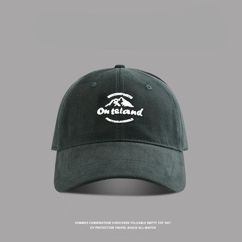 Deep green baseball cap with white "Outstand" mountain embroidery
