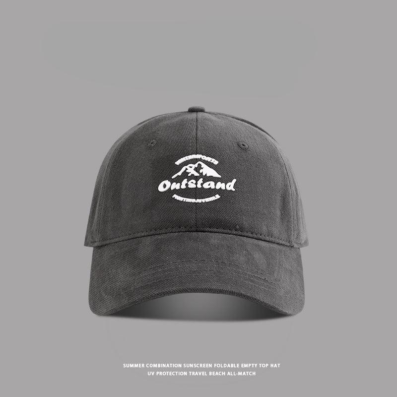 Dark gray baseball cap with "Outstand" and a mountain logo in white