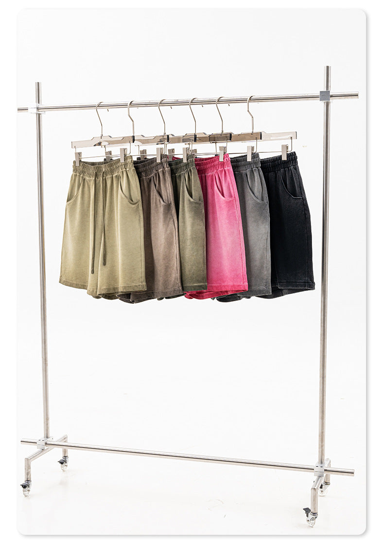 A clothing rack displaying multiple colors of washed cotton shorts including black, olive, taupe, gray and pink on hangers