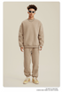 Model wearing beige monochrome sweatsuit with white sneakers against neutral backdrop