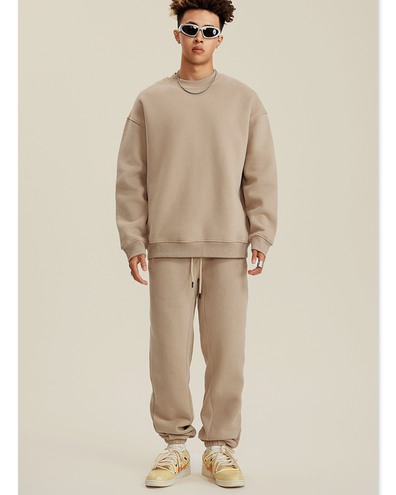 Model wearing beige monochrome sweatsuit with white sneakers against neutral backdrop