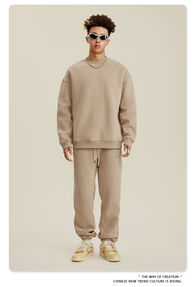 Model wearing beige monochrome sweatsuit with white sneakers against neutral backdrop