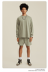 Man in sage green sweatshirt and shorts set with chain necklace, watch and white sneakers