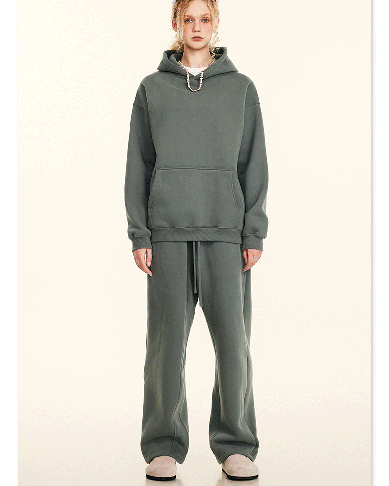 Model wearing sage green oversized hoodie and sweatpants set with cream slip-on shoes on neutral background