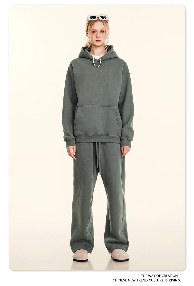 Model wearing sage green oversized hoodie and sweatpants set with cream slip-on shoes on neutral background