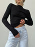 Black long sleeve fitted top with mock neck and ruched details, styled with light wash high-waisted jeans