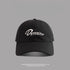 Black baseball cap with white Dynamism script embroidery against gray background"