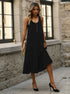 Black midi dress with gold buttons, model standing near stone wall, wearing black stiletto heels and gold jewelry