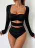 Model posing in a black cutout bodysuit with long sleeves and ruched details, highlighting a modern, edgy design.
