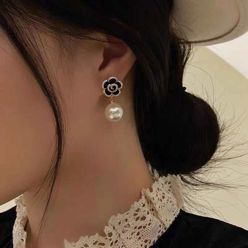 Black and white floral drop earring with crystal rim and pearl pendant, shown worn on ear with lace collar