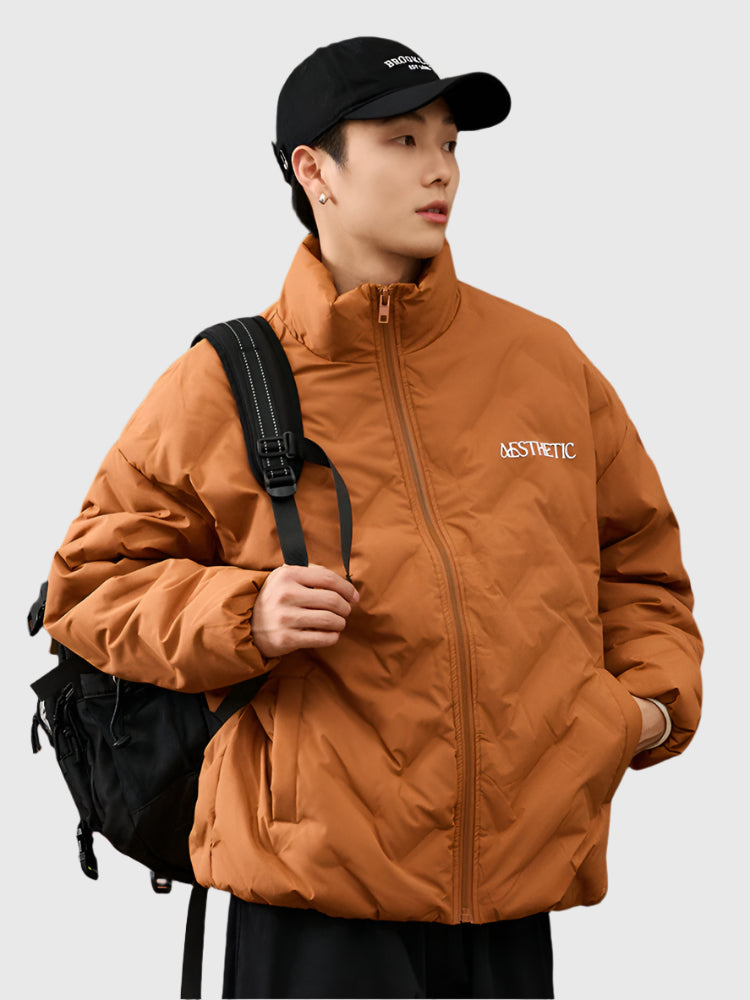 Man wearing camel brown Aesthetic puffer jacket with black backpack strap, styled with black baseball cap and white undershirt