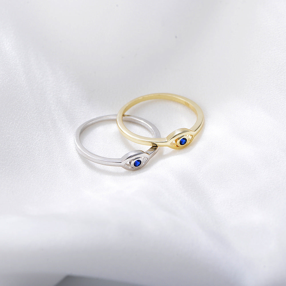 Gold and silver eye rings with blue sapphires displayed together on white background
