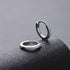 Close-up pair of zirconium set silver hoops on dark textured background