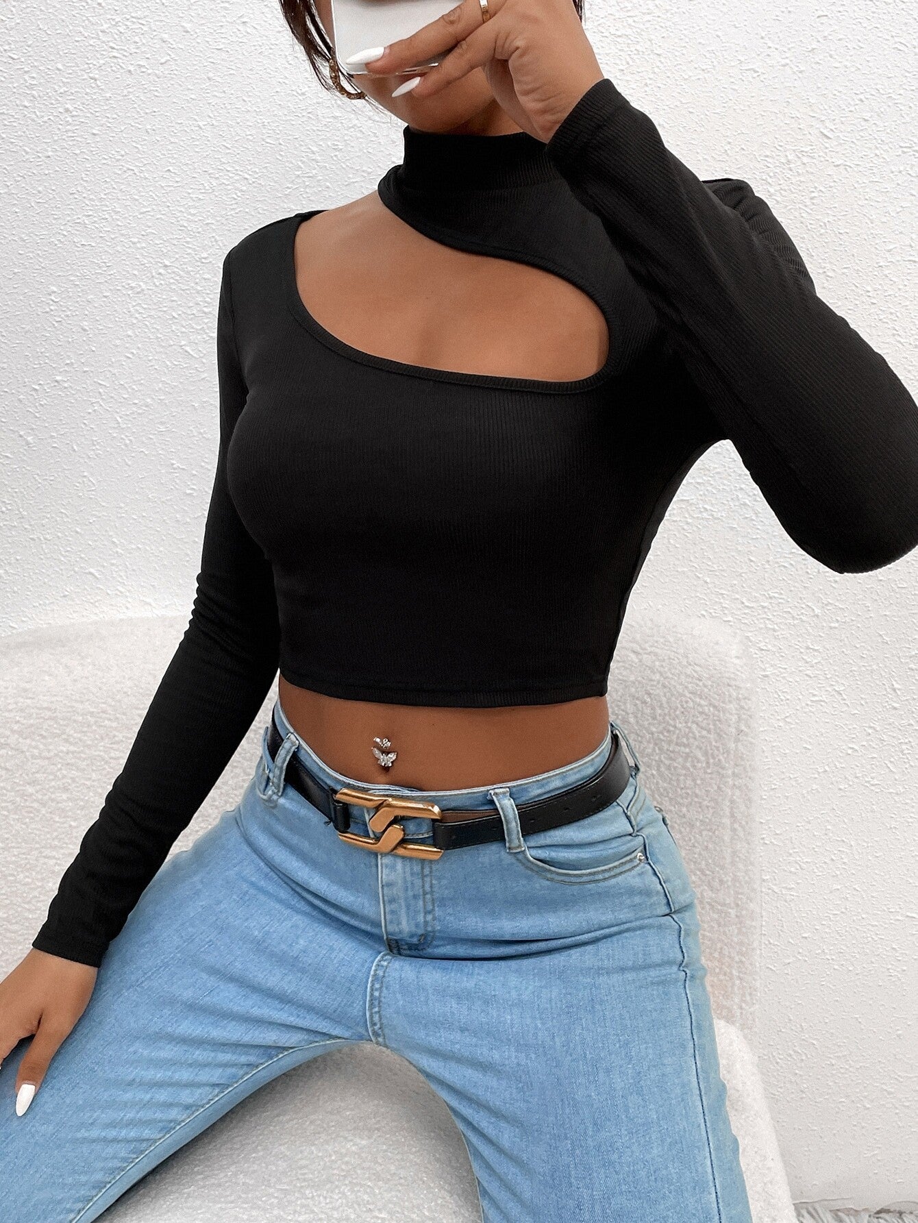 Detailed view of black long-sleeve crop top with unique cutout design and mock neck