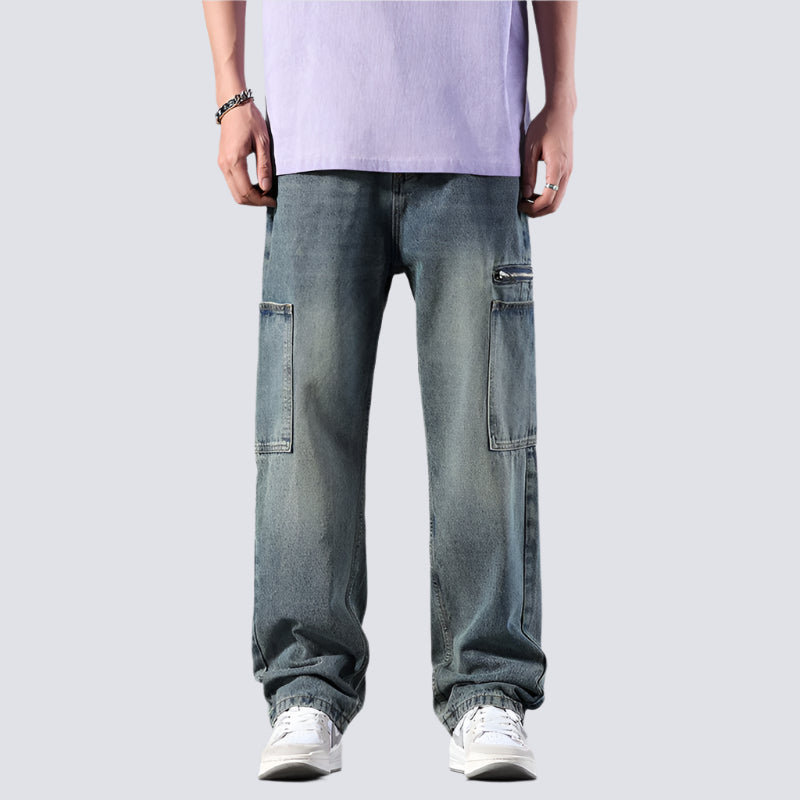 A model wearing faded blue cargo jeans with oversized utility pockets paired with lavender tee and white sneakers against white background