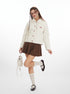 Woman wearing a white puffer jacket, brown skirt, and white shoes on a white background