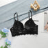 A black push-up bra with back closure and lace detailing arranged with blue roses and denim fabric. Magazine visible in corner