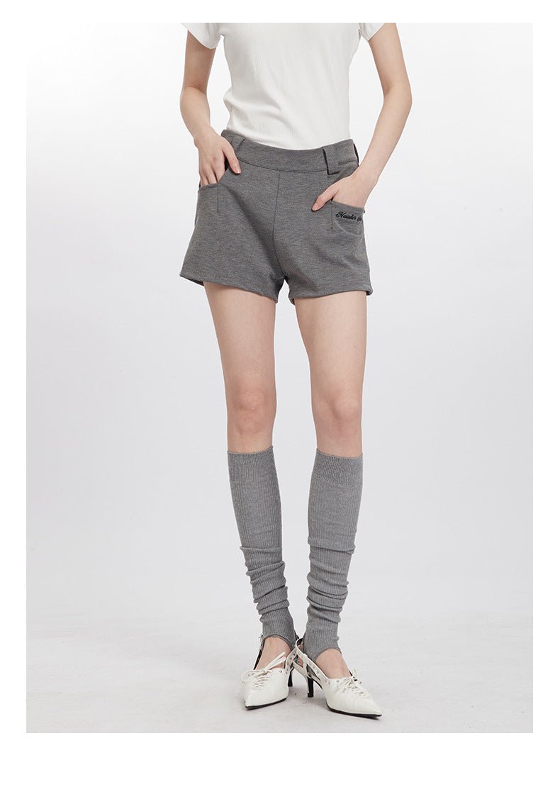 Front view of gray shorts with structured waist, worn with knee socks and vintage-style white heels