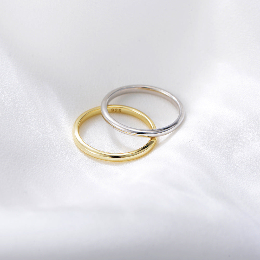Gold and silver 925 stackable band rings overlapping on white satin surface in studio lighting