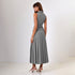 A woman wearing a gray sleeveless blazer vest with back belt detail and pleated midi skirt, shown from behind against white background