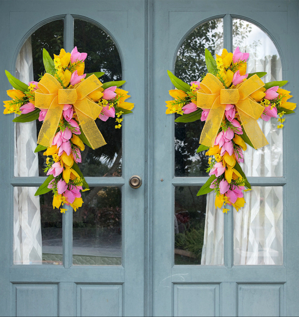  Matching yellow and pink floral cross wreaths with bows, symmetrically displayed on blue double doors for a festive look.
