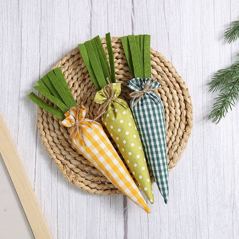 Three fabric carrots in yellow gingham, green polka dot, and green gingham patterns, arranged on a woven mat.