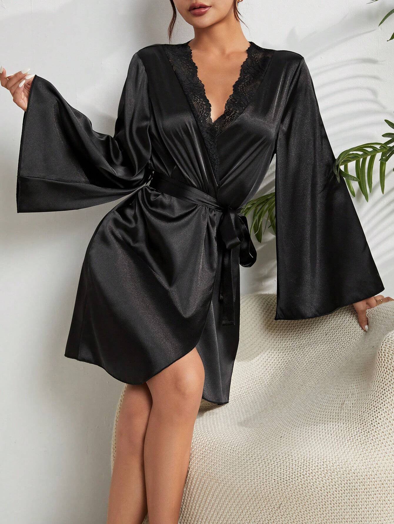 Side view of woman seated wearing black silk robe with dramatic bell sleeves and lace trim neckline