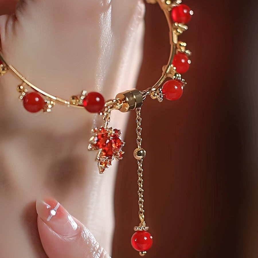 Elegant red agate bracelet with maple leaf charm and gold-tone details