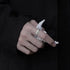 Lifestyle photo of silver patterned ring on hand with white paper, captured in dark ambient setting