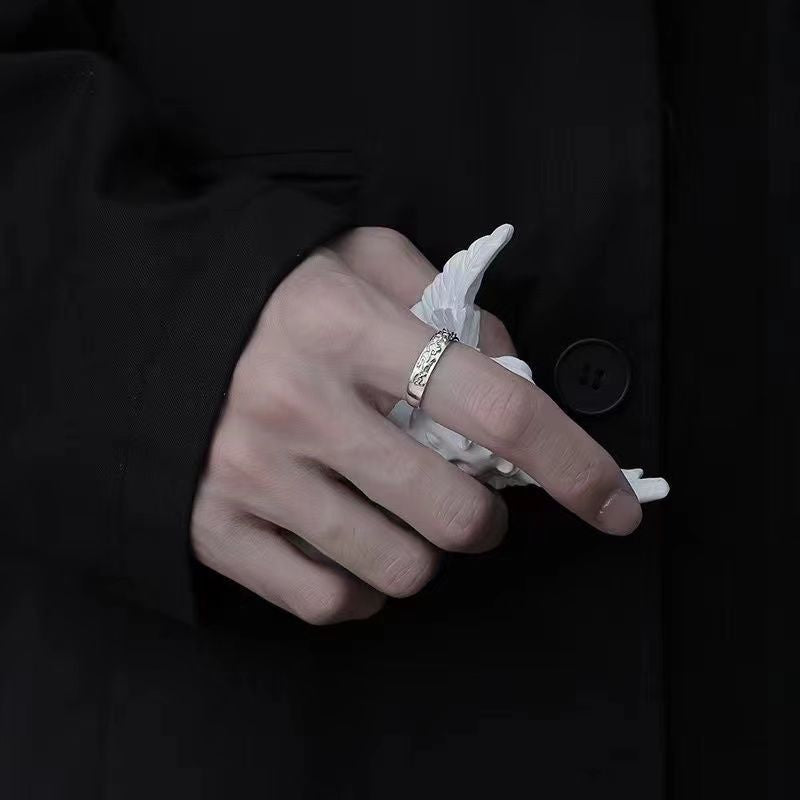Lifestyle photo of silver patterned ring on hand with white paper, captured in dark ambient setting