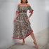 Woman wearing an off-shoulder leopard print maxi dress, slightly lifting the skirt while posing against a neutral backdrop.