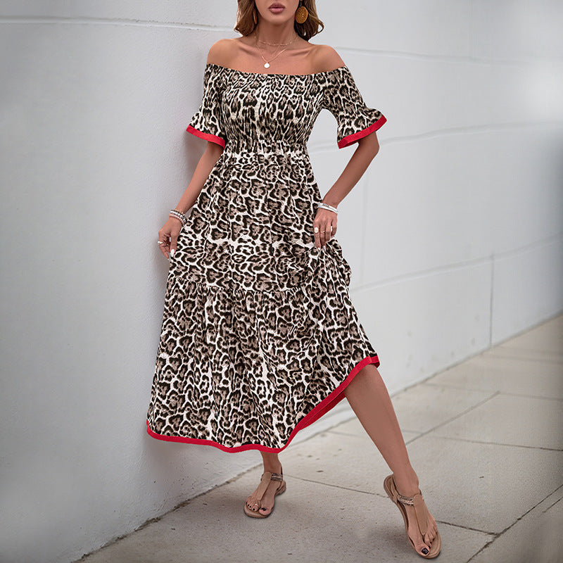 Woman wearing an off-shoulder leopard print maxi dress, slightly lifting the skirt while posing against a neutral backdrop.