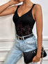 Side view of woman in black lace bodysuit paired with high-waisted jeans and black clutch.