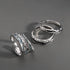 Four textured silver rings displayed on a gray surface