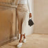 Model in cream high-waisted cargo midi skirt with side pockets and slit, wearing white platform sneakers