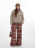 Model in full-length pose wearing beige sherpa jacket, brown beanie, plaid pants and carrying small brown bag against white backdrop