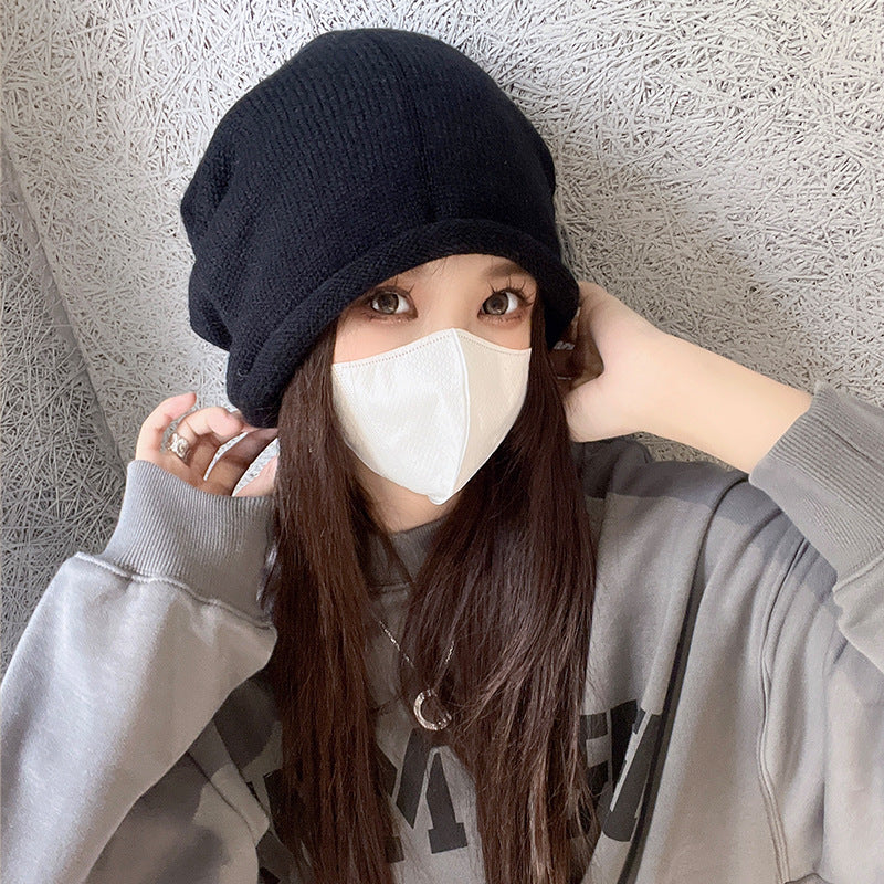 Black slouchy beanie with white face mask and gray sweatshirt