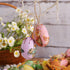  Close-up of two vintage-style Easter egg ornaments with rabbit prints, hanging from a white tree branch.