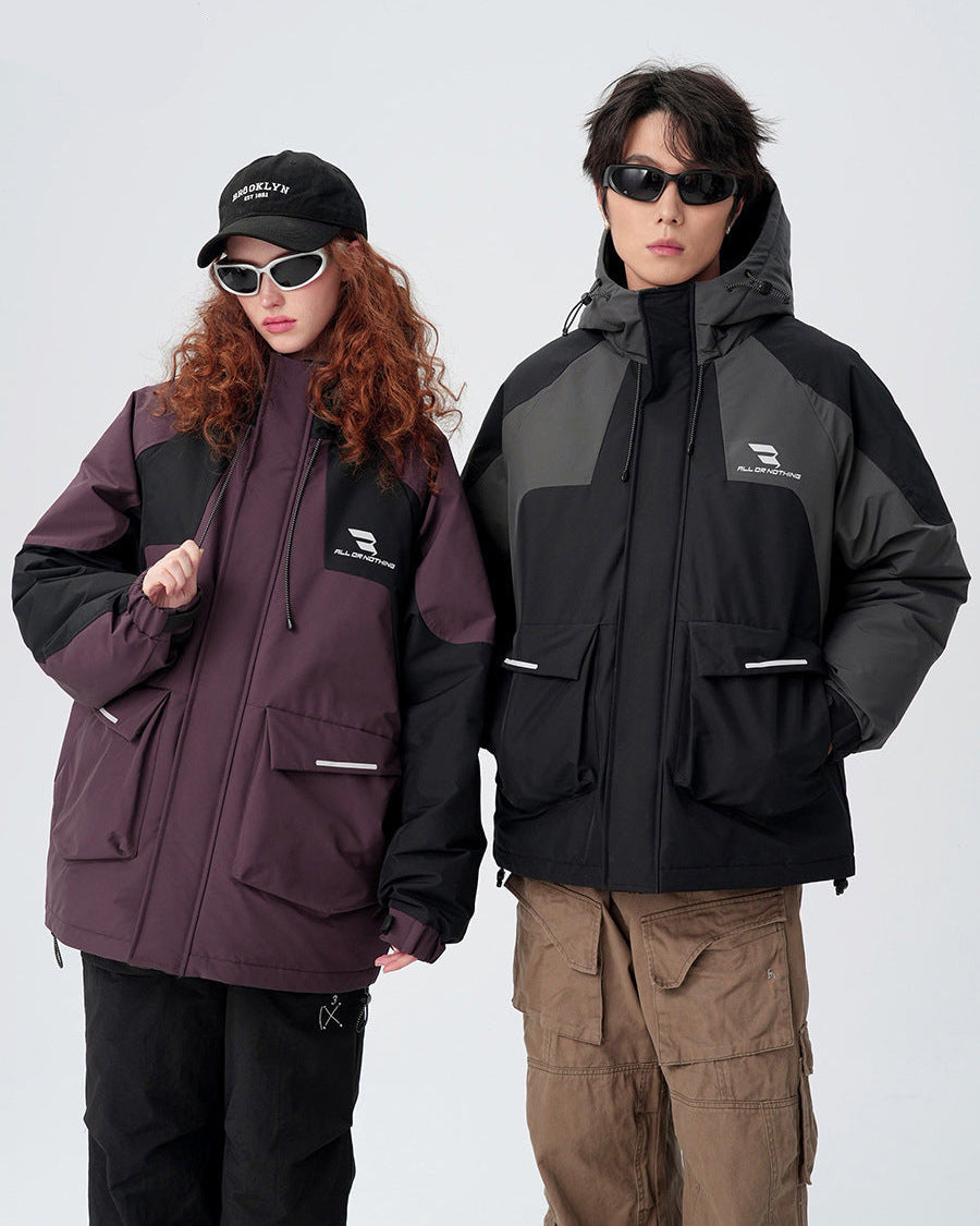 A man and woman wearing contrasting All Drifting jackets stand against white background - his in black/gray, hers in plum/black