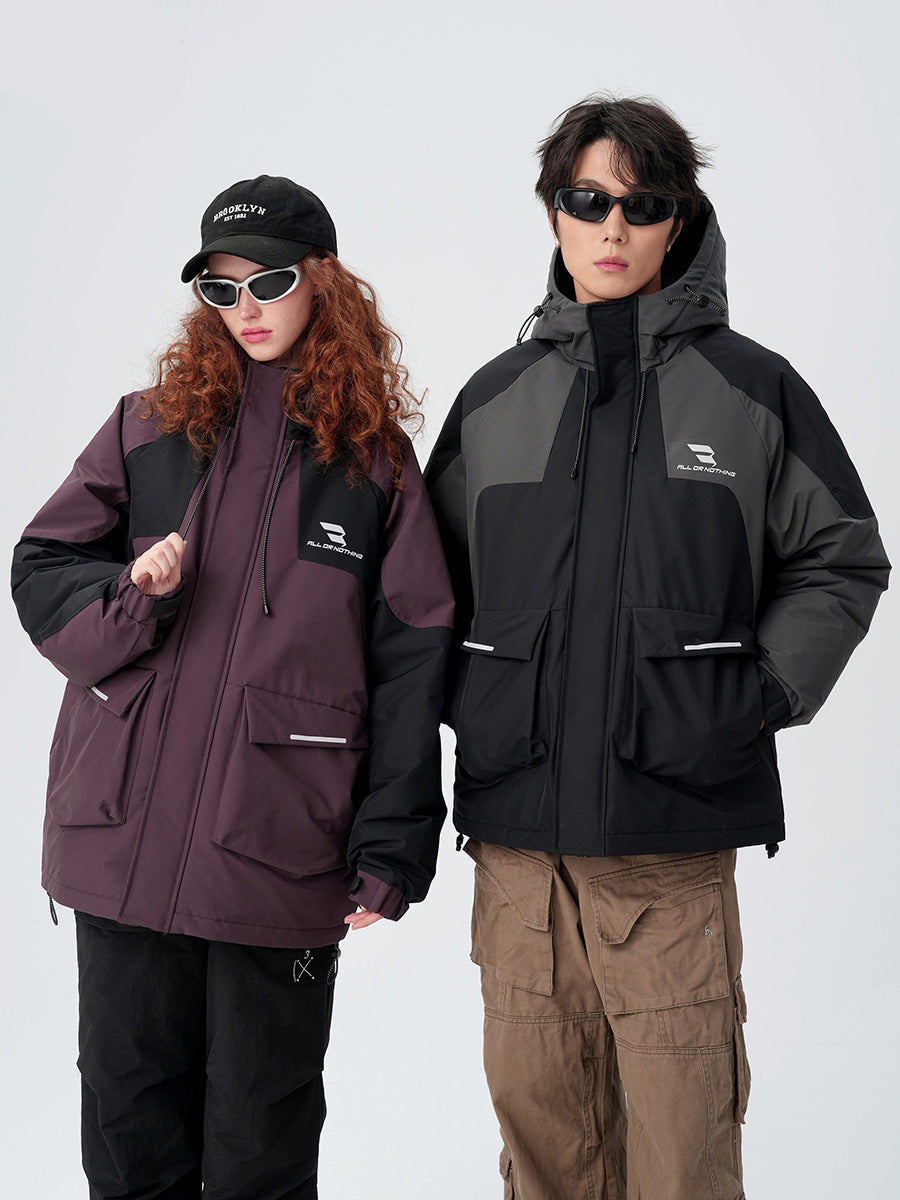 A man and woman wearing contrasting All Drifting jackets stand against white background - his in black/gray, hers in plum/black