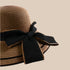 A close-up of a khaki straw sun hat's black bow detail, highlighting the fine texture and craftsmanship.