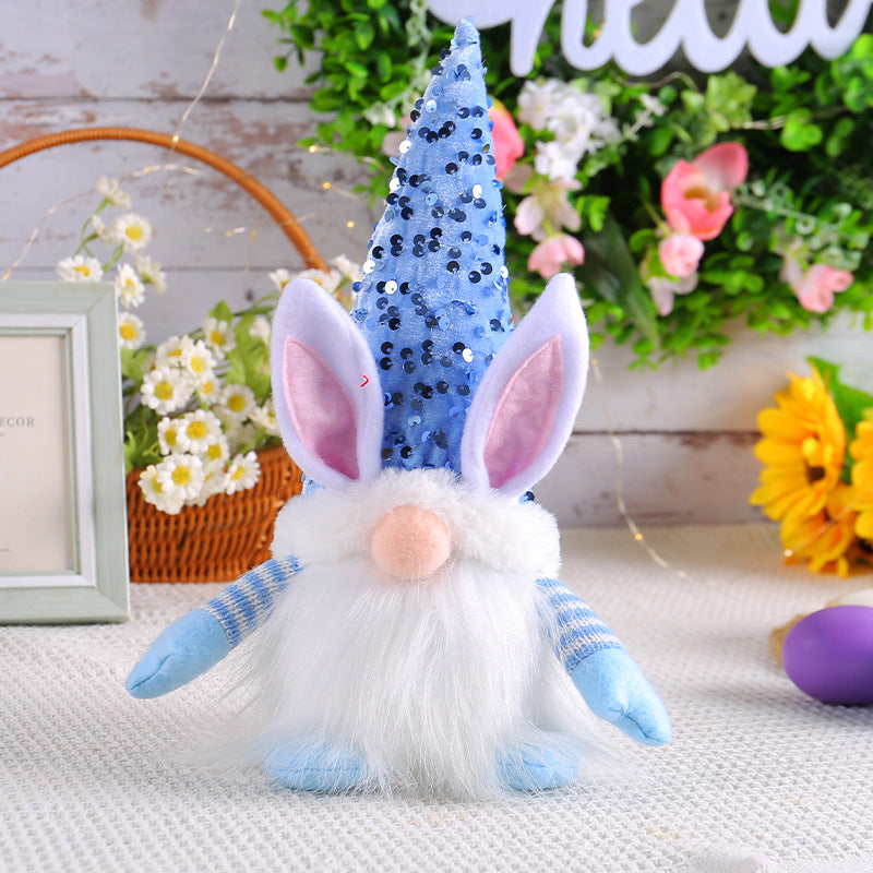 Blue sequin-hat bunny gnome plush toy with long ears and white beard, displayed on a decorative table.