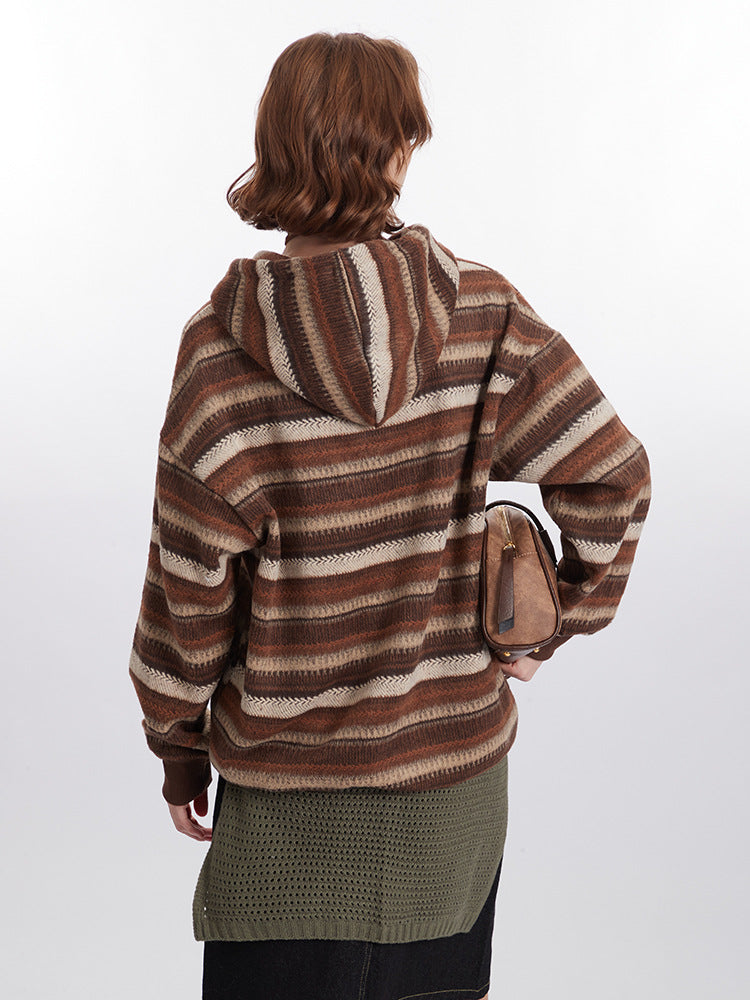 Back view of model wearing textured brown striped hoodie jacket, showing olive green knitted belt detail and carrying matching brown handbag