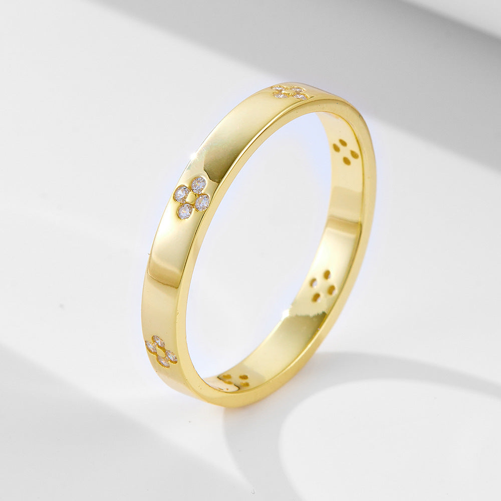 Gold wedding band with small diamond flower motifs spaced around polished ring, featuring tiny crystal clusters on white surface