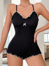 A black ribbed romper with white ruffle trim, spaghetti straps, and a small bow detail at the chest, worn by a model indoors.